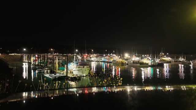 Fishing harbour at night with boats and reflections on calm water