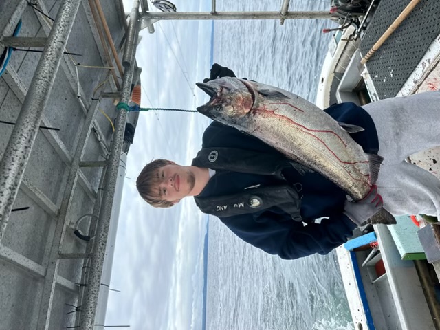 A young crew member holding a large salmon on deck